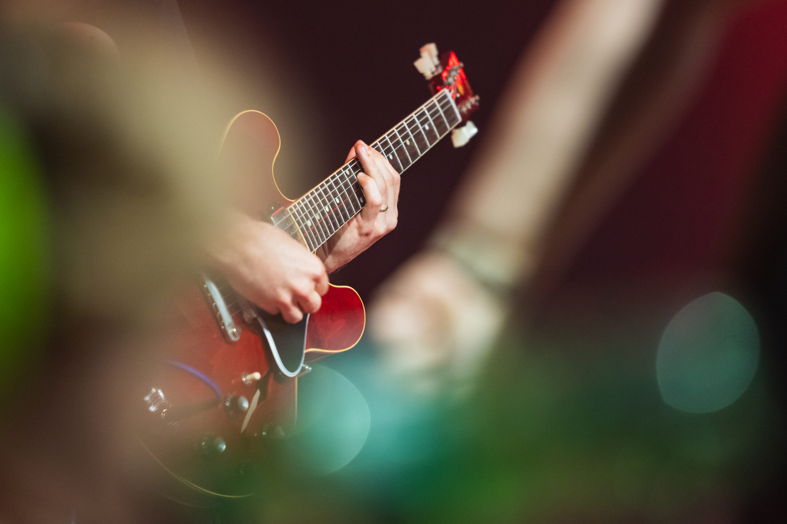 Mit der Eventfotografie fängt Fabienne Felder alle Details eures Events ein. Wie zum Beispiel ein Gitarrist, der auf einer roten Gitarre spielt.